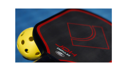 Close-up of a pickleball paddle with a yellow pickleball on a blue background